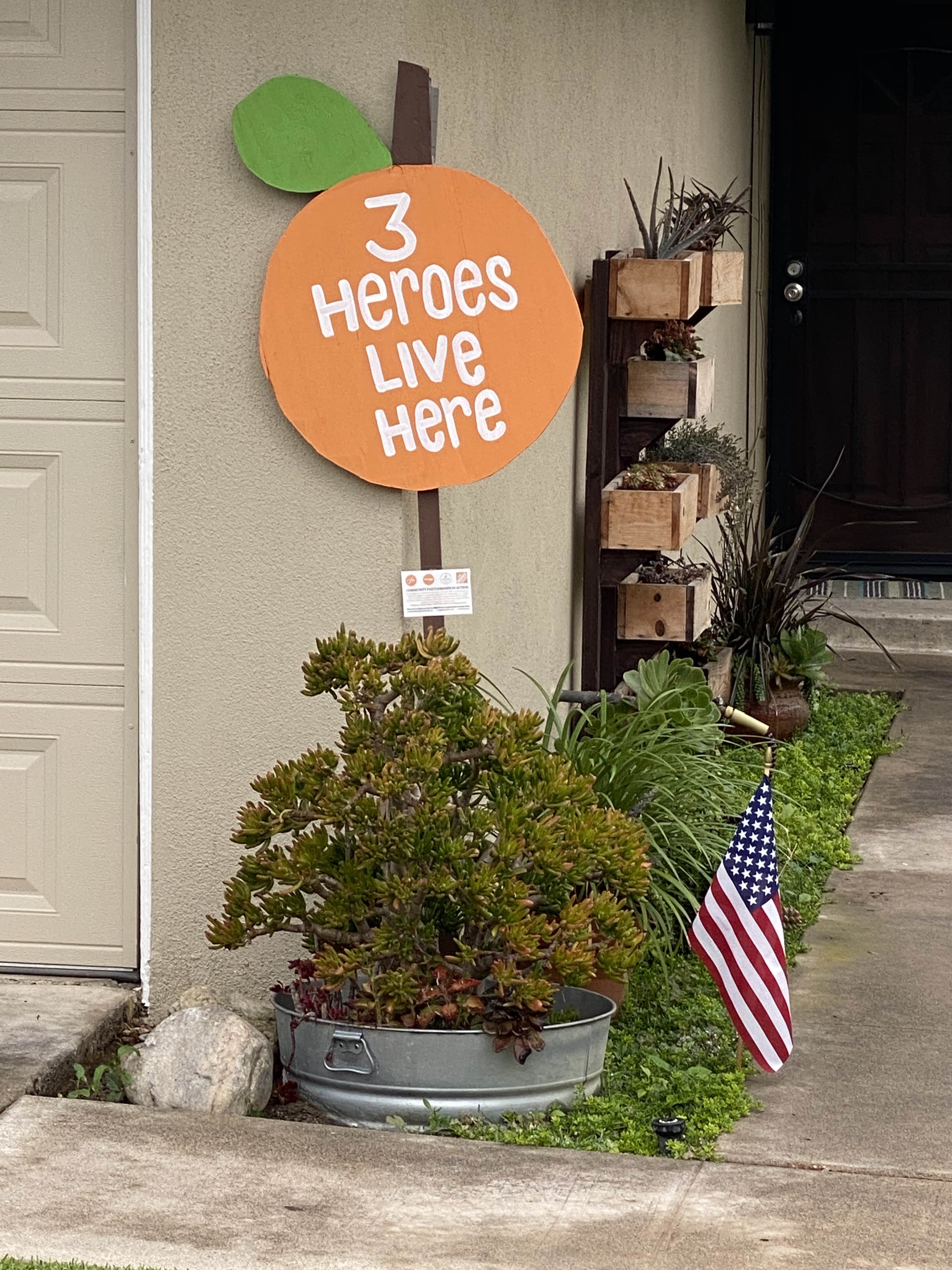 Picture of  sign in the shape of an Orange with white text that says "3 Heroes Live Here".